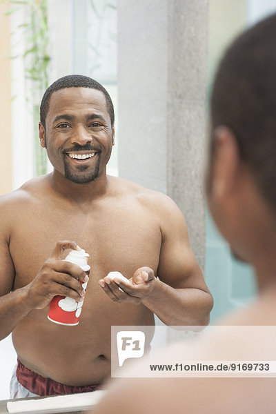 African American man shaving in bathroom