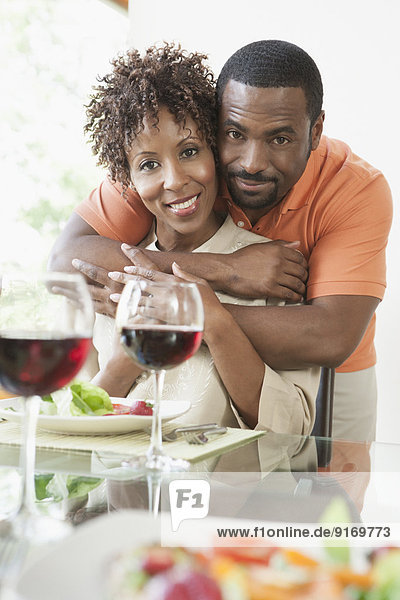 African American couple hugging at dinner table
