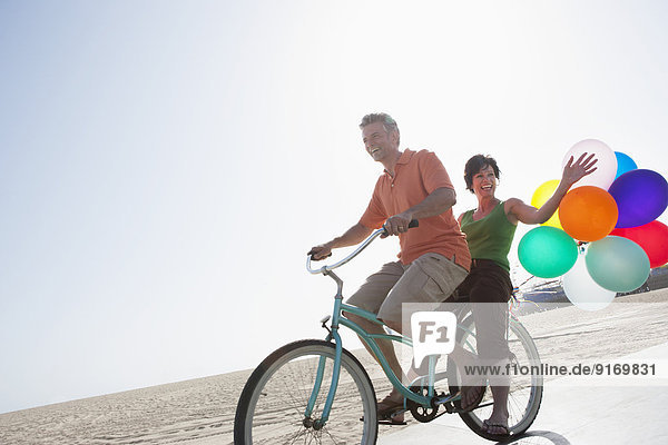 Caucasian couple riding bicycle by beach