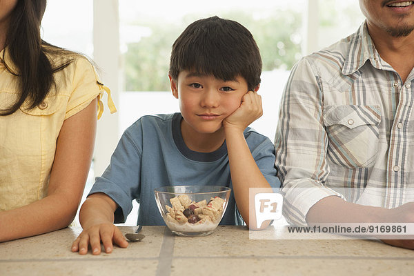 Boy sitting between parents at breakfast table