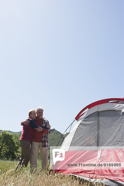 Senior Caucasian couple admiring tent in field