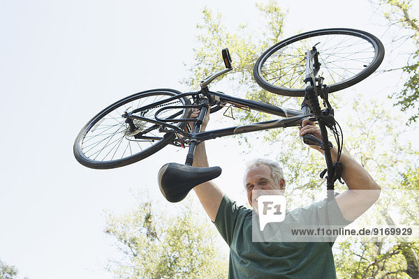 Senior Caucasian man holding bicycle outdoors