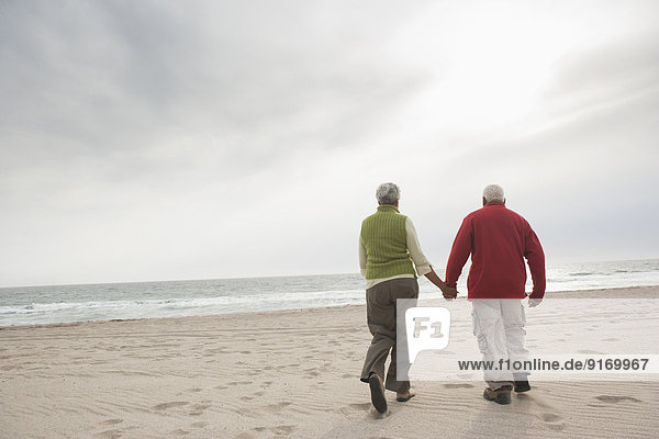 Mixed race Senior couple walking on beach