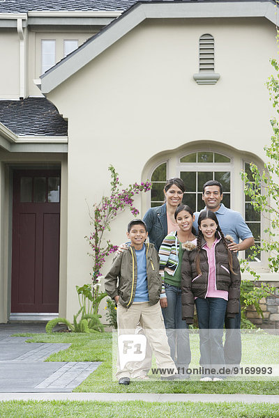 Hispanic family smiling outside home
