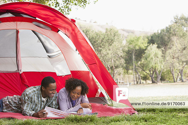 Couple reading newspaper together in tent