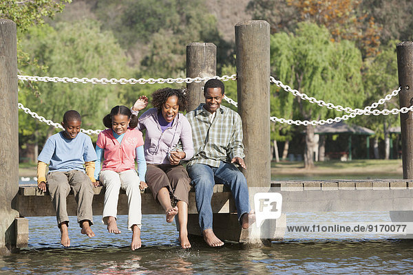 Family sitting on wooden dock in lake
