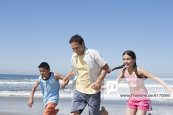 Hispanic father and children playing on beach