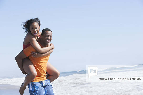 Man carrying girlfriend on beach