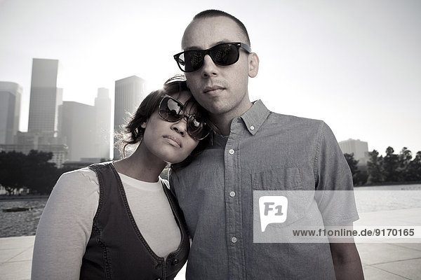 Couple wearing sunglasses on urban waterfront