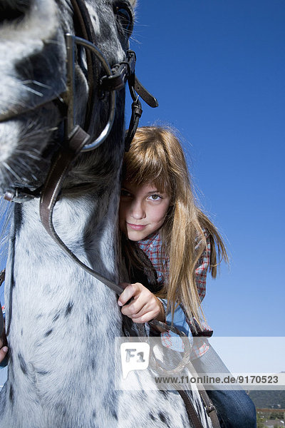 Mixed race girl riding horse on ranch