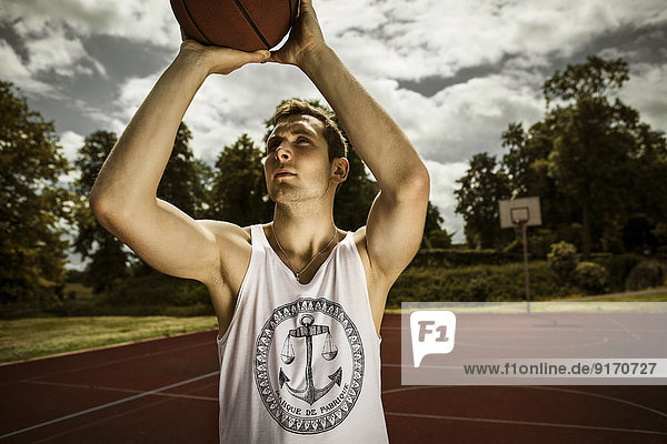 Junger Basketballspieler  der auf Basketballkorb zielt