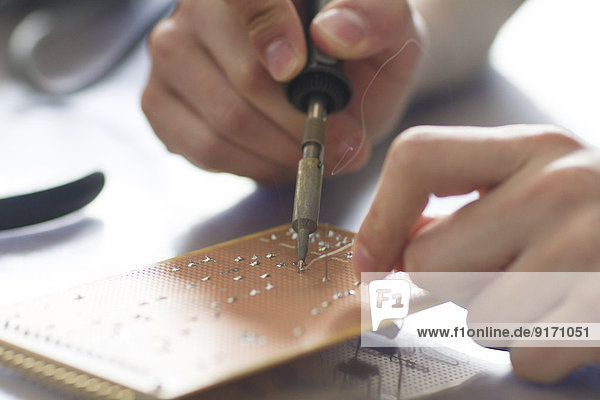 Electronic apprentice soldering circuit board at workshop  detail