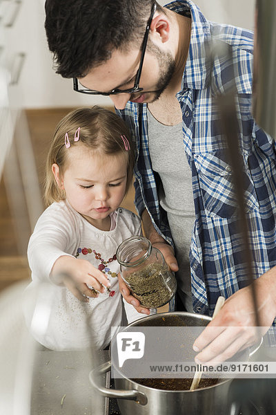 Father and daughter cooking in kitchen