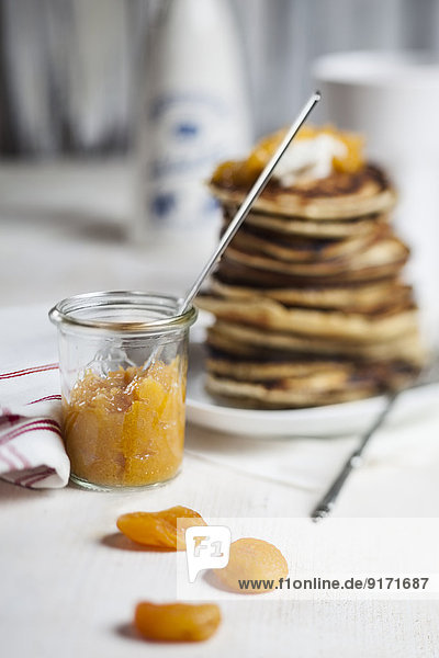 Stapel amerikanischer Pfannkuchen  Glas Aprikosensoße und getrocknete Aprikosen auf dem Tisch