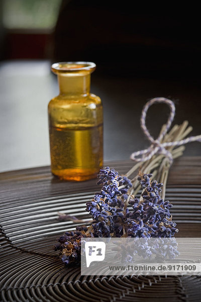 Lavender oil in a glass bottle,  twigs of lavender,  Lavandula angustifolia