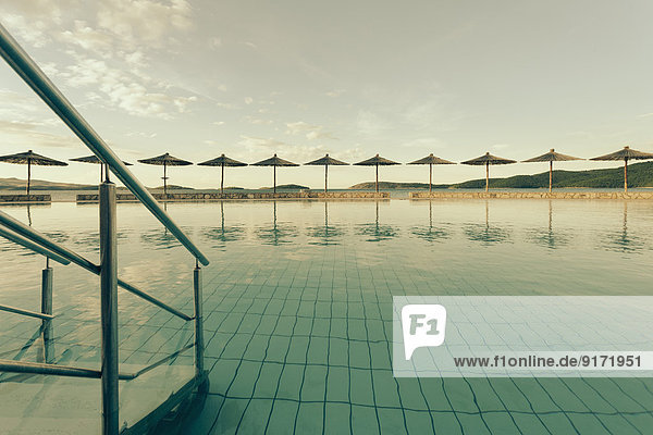 Kroatien  Sibenik  Sonnenschirme  Schwimmbad einer Hotelanlage  Abendstimmung