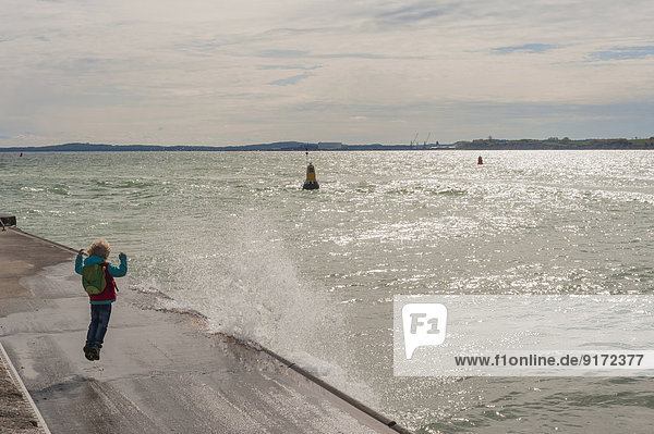 Germany  Mecklenburg-Western Pomerania  Ruegen  Sassnitz  Excited boy on pier with splashing water