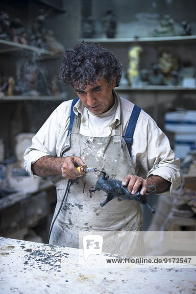 Germany,  Munich,  Art foundry worker finishing figurine