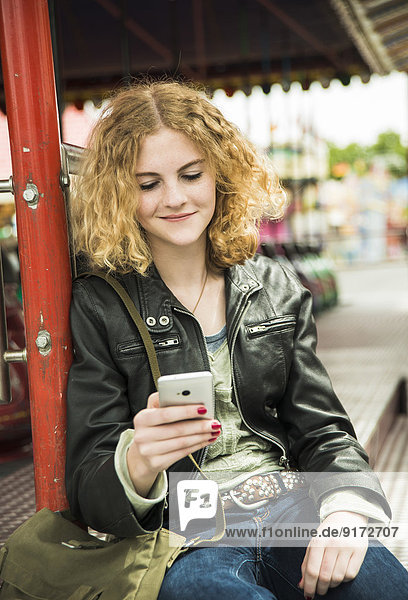 Portrait of teenage girl using smartphone at fun fair