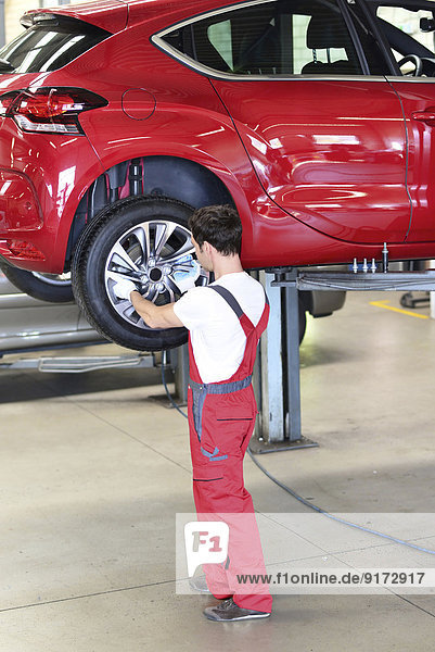 Car mechanic in a workshop changing tire