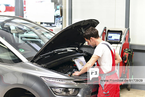 Car mechanic in a workshop using modern diagnostic equipment
