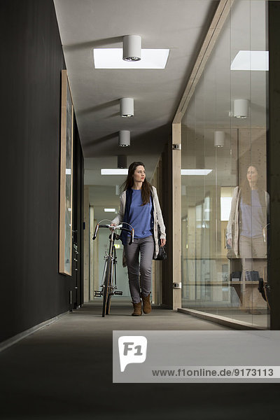 Business woman arriving at office with racing cycle