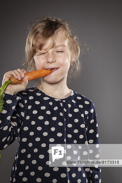 Porträt eines kleinen Mädchens beim Essen einer Karotte
