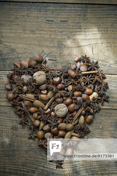 Herz aus Sternanis,  Nüssen und Zimtstangen auf Holz
