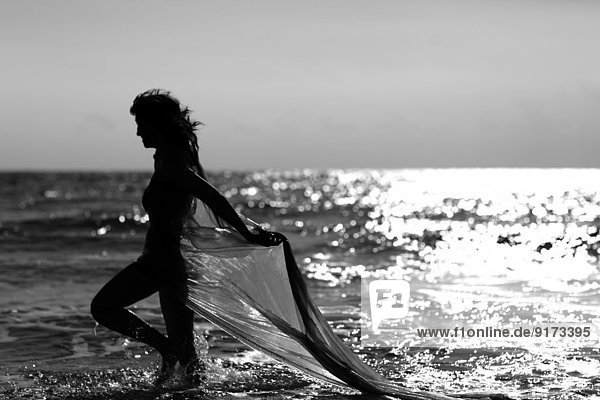 Silhouette of young woman walking at the sea