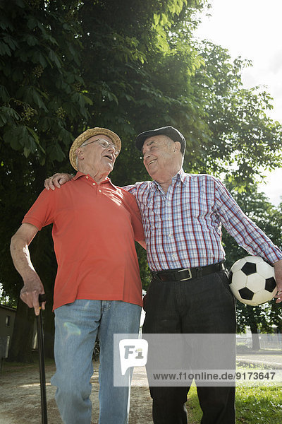 Two old friends walking in the park with football