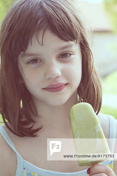 Porträt eines träumenden Mädchens mit grünem Eis am Stiel