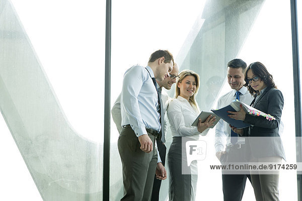 Businesspeople in office with woman using digital tablet