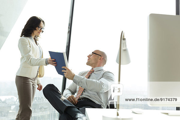 Businessman and businesswoman with documents in office