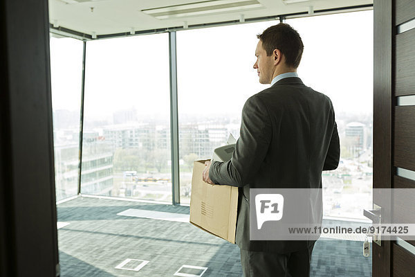 Businessman carrying cardboard box in office