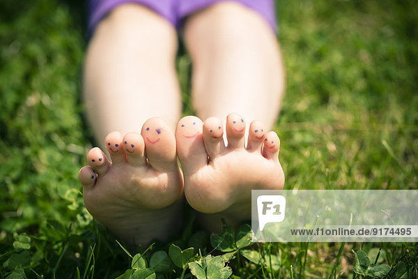 Kleine Mädchenfüße mit bemalten Zehen im Gras liegend