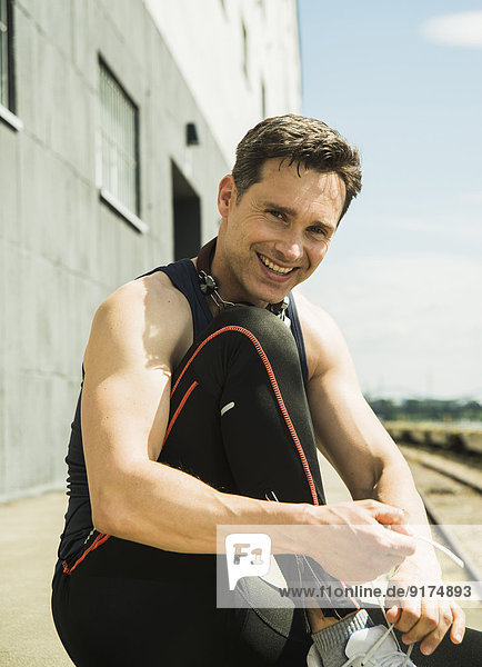Portrait of smiling jogger tying his shoes