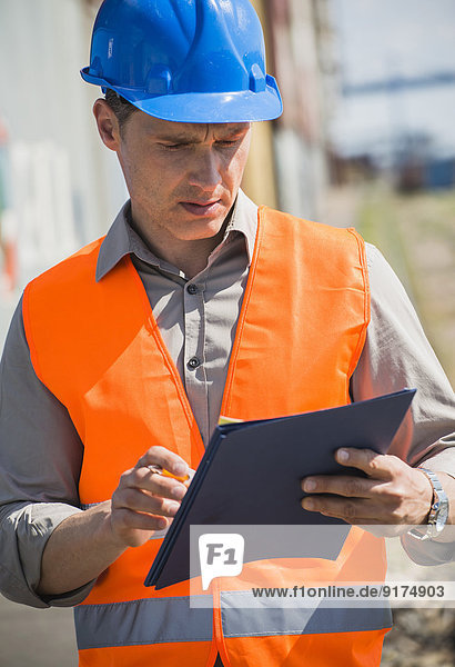 Portrait of man with blue safety helmet checking cargo containers
