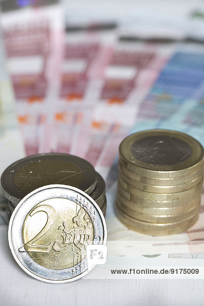 Sortierte Euro-Banknoten und Stapel von einer und zwei Euro-Münzen  Nahaufnahme