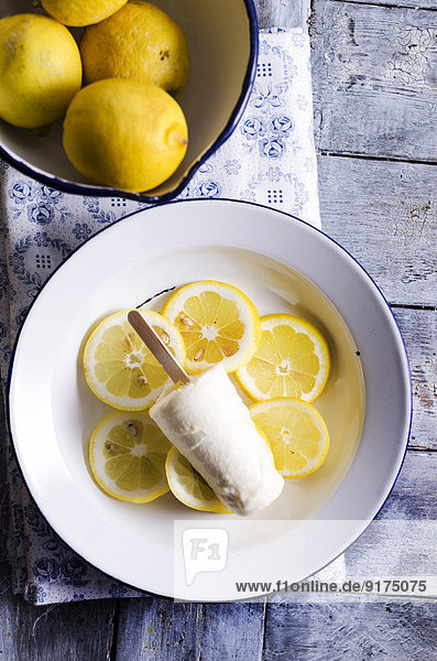 Schale mit Zitronen und Teller mit hausgemachtem Zitronencremeeis auf Zitronenscheiben  erhöhte Ansicht