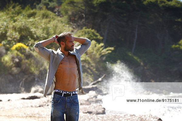 Griechenland  Ionische Inseln  Korfu  fröhlicher Mann mit den Händen hinter dem Kopf am Strand