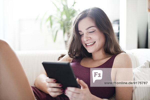 Portrait der lächelnden jungen Frau mit Tablet-Computer zu Hause