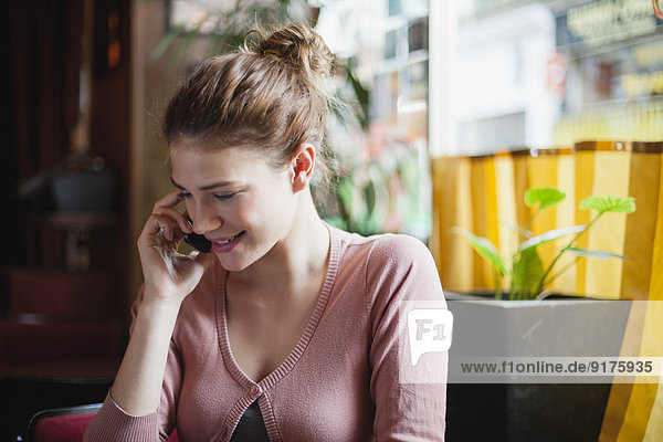 France  Paris  portrait of young woman telephoning with her smartphone in a cafe