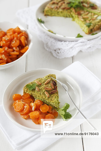 Gebackene Erbsenkuchen mit Pinienkernen  garniert mit glatter Petersilie und gedämpften Karotten