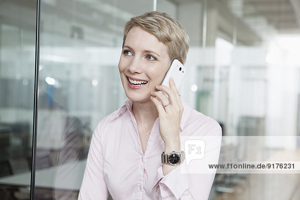 Deutschland  München  Geschäftsfrau im Büro  mit Smartphone