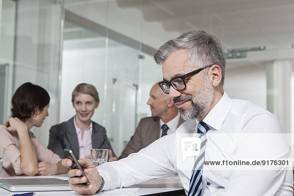 Germany  Munich  Businesspeople in conference room  man reading text message