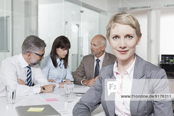Germany  Munich  Businesspeople in conference room  woman in foreground looking to camera