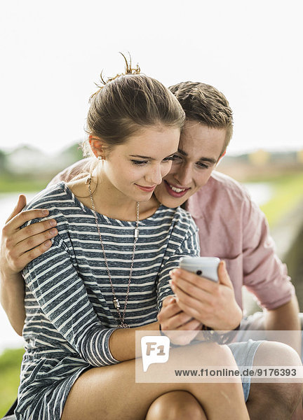 Junges Paar schaut auf Smartphone