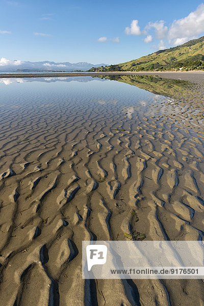 New Zealand  Tasman  Golden Bay  Pakawau  reflections of clouds in the water and structures in the sand at low tide