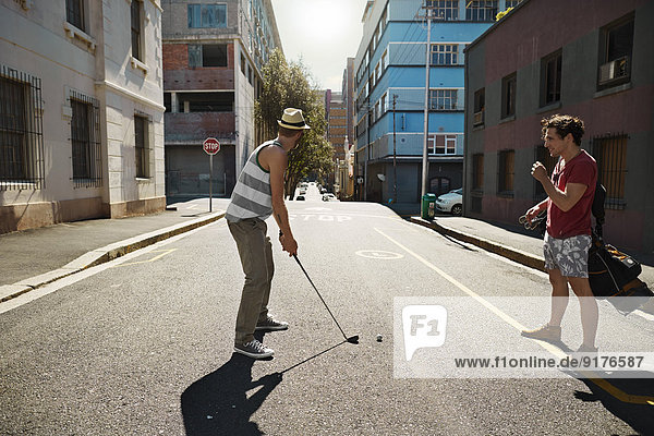 Two friends playing urban golf in the city