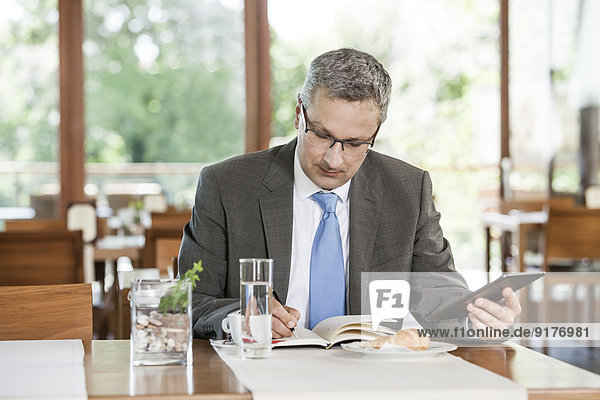 Businessman in restaurant writing in notebook